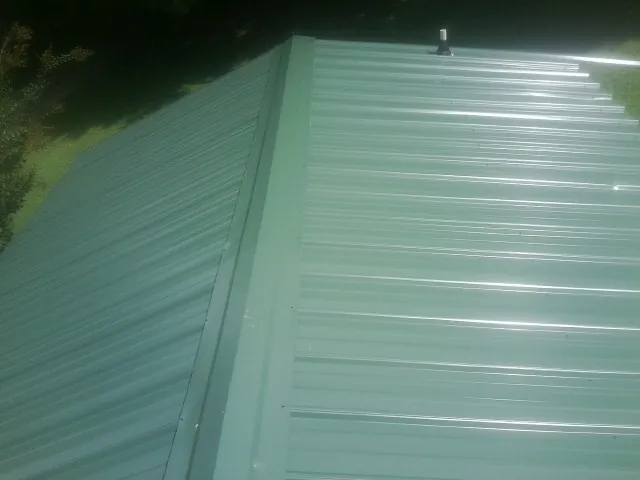 New green metal panels meeting at the ridge of a roof — Flat Roof Repair work by our crew in Kempton