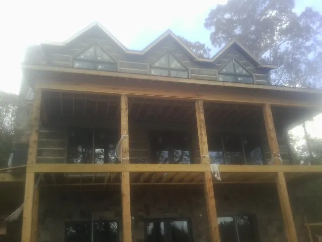 Dormers and porch framing on a large log home under construction — Roof Coating work by our crew in Kempton