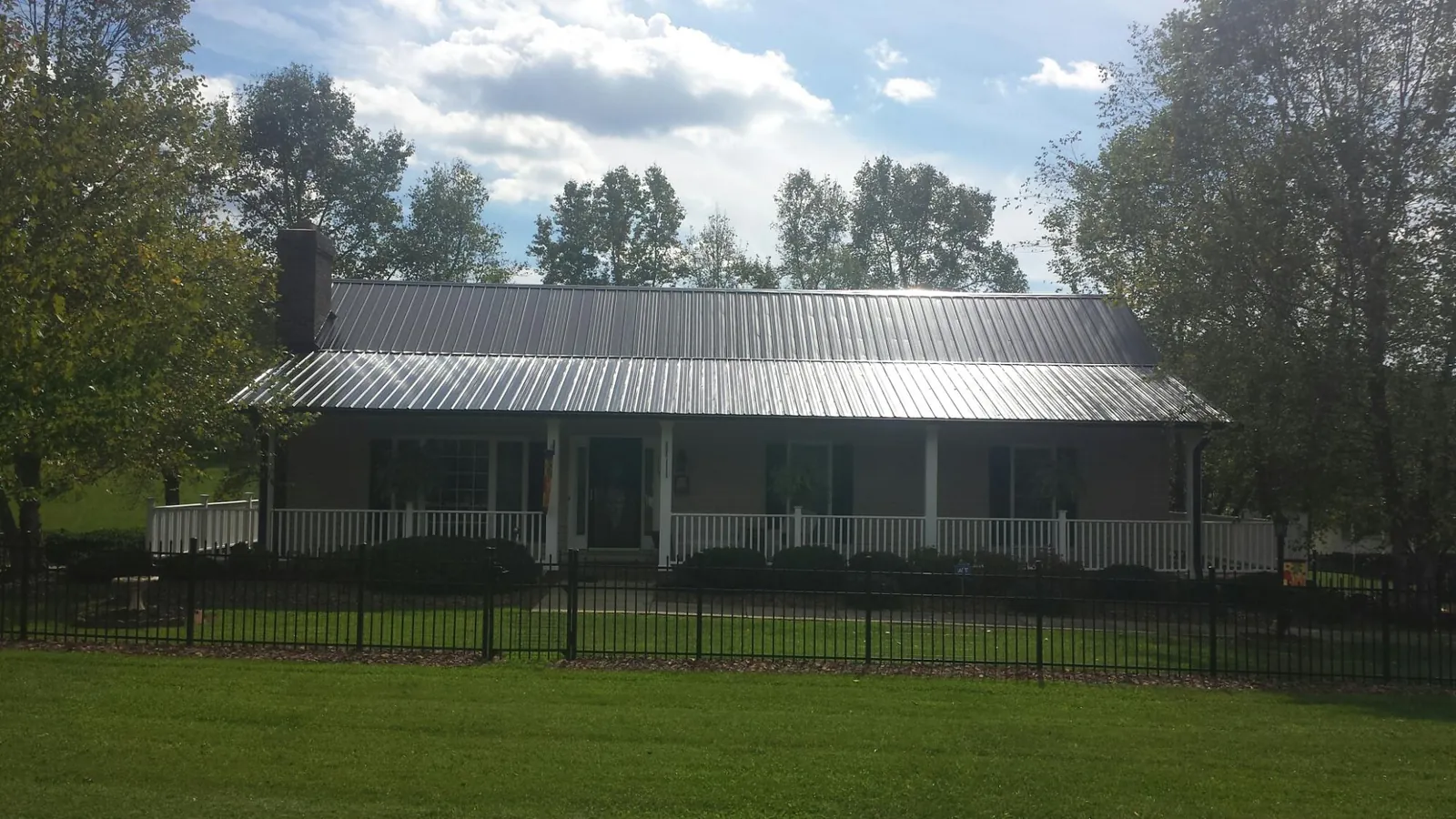 Gray metal roof on a brick ranch with a full width front porch — Gutter Guard Installation work by our crew in Kempton